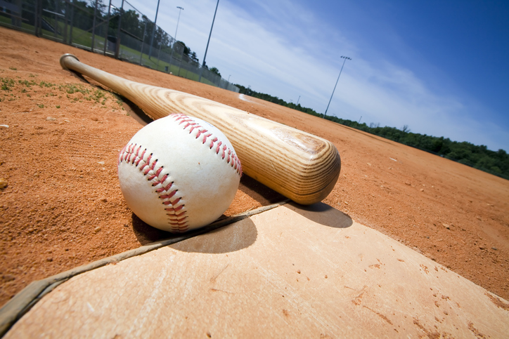 Baseball and bat on home plate of a ballpark