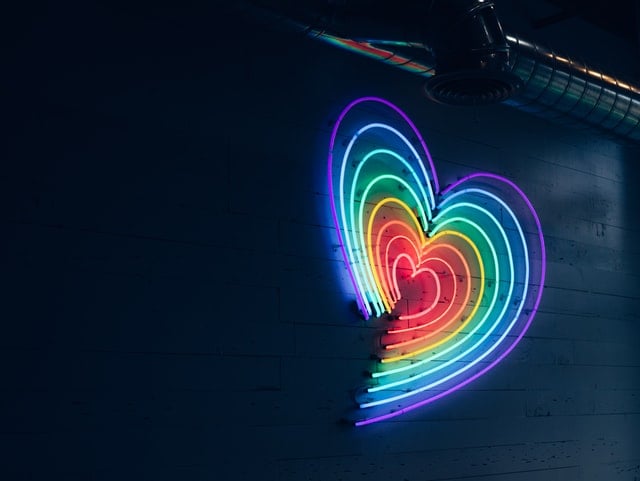 A multi-colored neon heart, with the red at the center growing into a rainbow, representing the re-activation of loving feeling.
