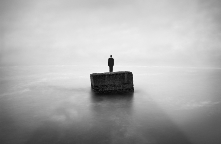 Man is thinking on the edge of stone. Image was shot with long exposure, therefore water looks in this way. Only man was pasted and horizon was removed, other on the photo is original. Man was pasted from another image