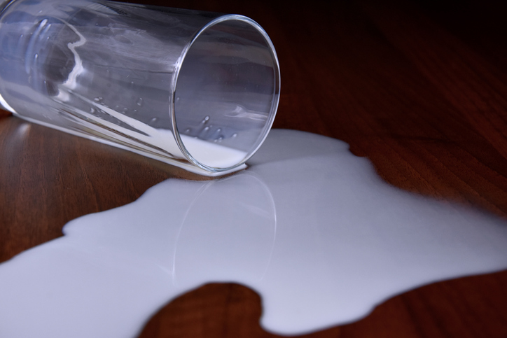 Glass of spilled milk close-up.