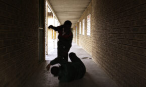 Two school kids fight in a dark passageway of their school, almost silhouette.