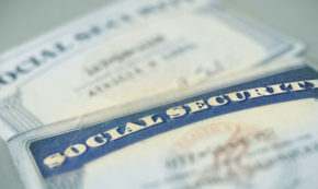 photo shows the close-up of two social security cards on a table, blurred.
