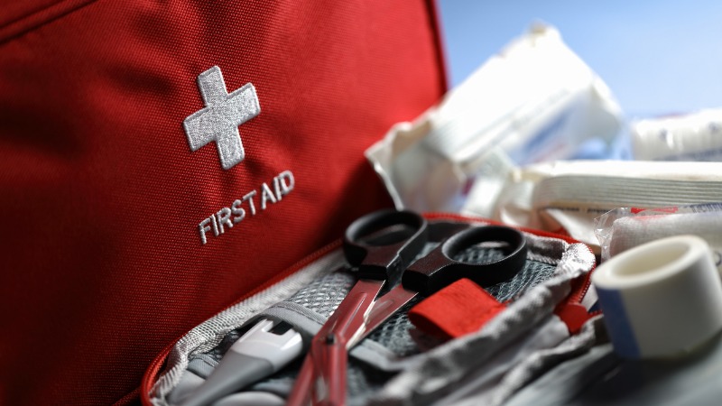 Photo shows a red first aid bag and first aid supplies outside of the bag.