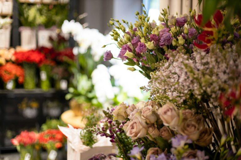 Image shows a close-up of the inside of a flower shop, with focus on a bouquet of cream colored roses while other flowers are blurred in the frame.