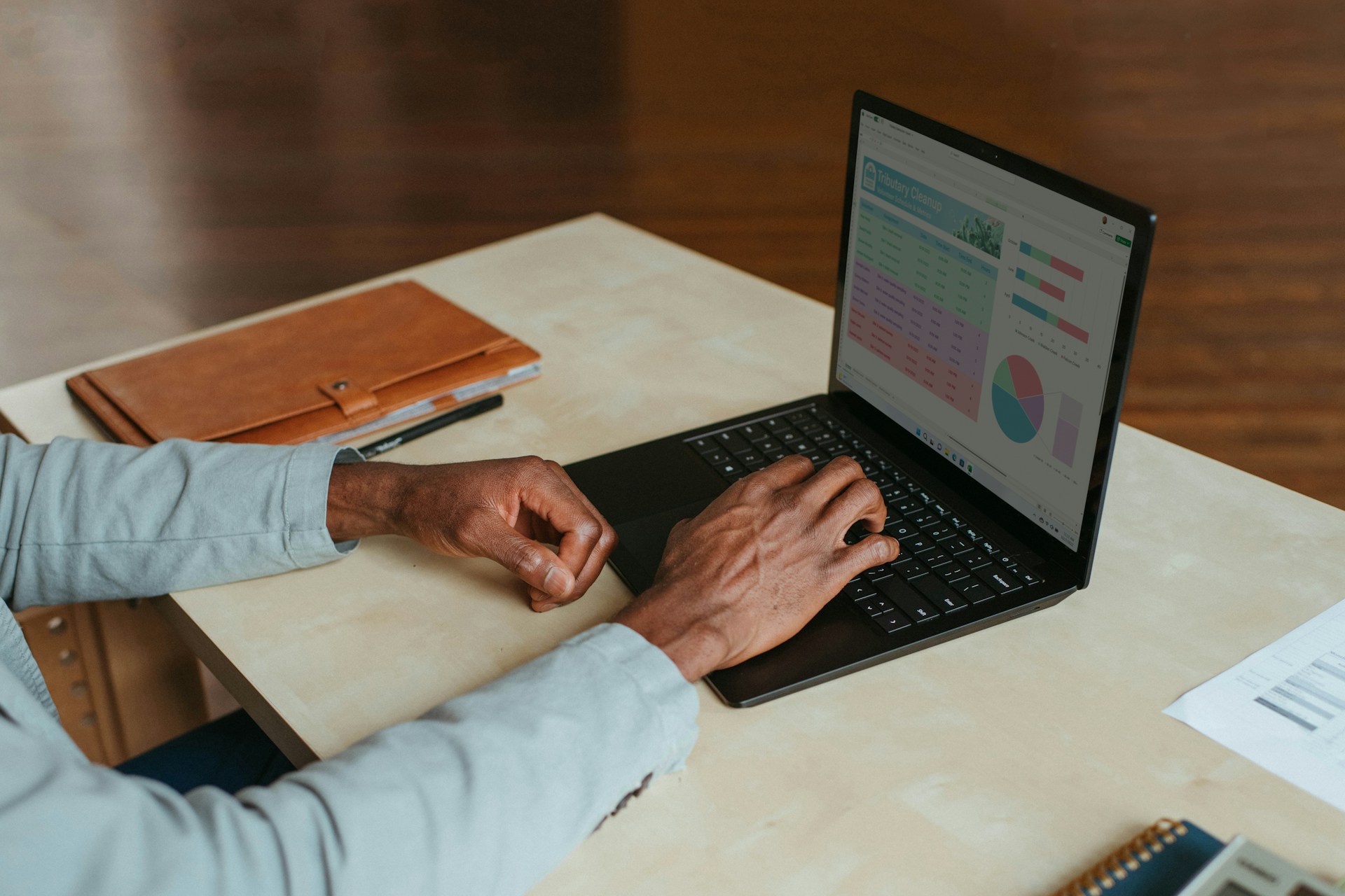Image shows a laptop with business financials graphed on the monitor, and the hands of the entrepreneur on the keyboard.