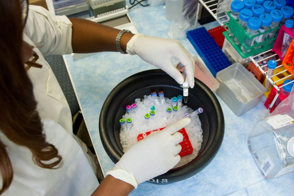 Scientist handling labeled test tubes in ice bucket inside a laboratory workspace