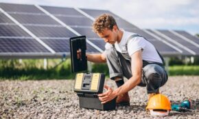 A worker using a toolbox at a solar panel installation site representing portable solar generator setup and maintenance